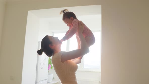 Happy Mother Lifting and Playing with a Satisfied Baby in the Morning