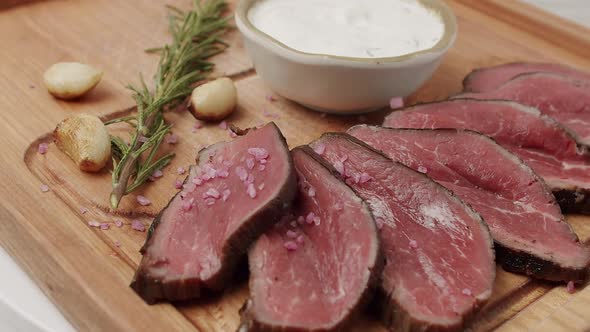 Grilled Rare Medium Beef Meat with Garlic and Rosemary in a Woden Plate