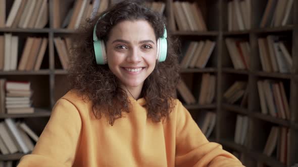 Happy Latin Teen Girl Student Wear Headphone Look at Camera Learn Online Laptop