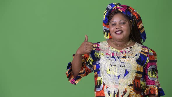 Overweight Beautiful African Woman Wearing Traditional Clothing Against Green Background