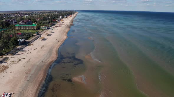 Beautiful flight in summer over the beach. People are resting near the sea. Houses for tourists.