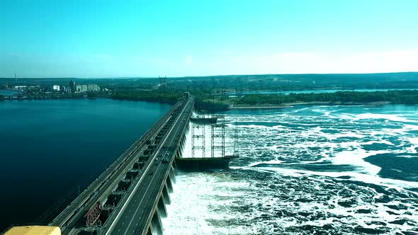 Seething Water Near a River Dam, Seen From a Copter. Bridge Over the Dam, Cars Drive Over the Bridge