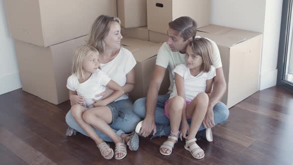 Happy Family Couple and Two Daughters Sitting on Floor