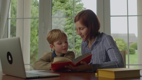 Young 30s Mother Reading Book with Her Son at Home