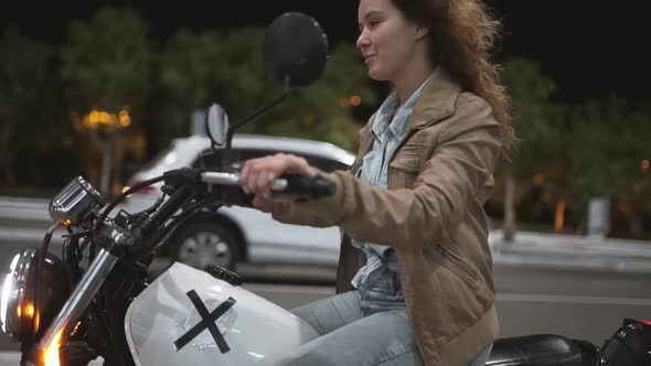 Beautiful Young Woman Riding an Old Cafe Racer Motorcycle on Street