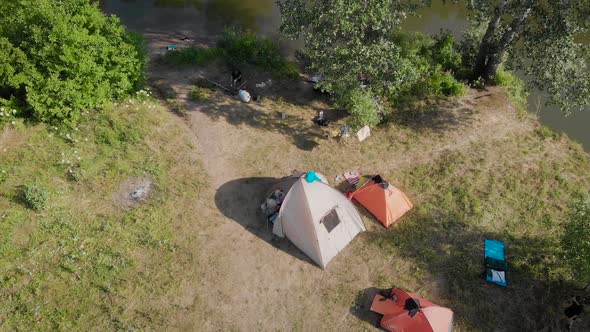 A Small Camp in the Fields. Tourists Stopped in a Beautiful Natural Place with Three Tents, Cook