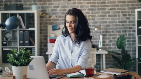 Portrait of Cheerful Office Worker Using Laptop Then Looking at Camera Smiling