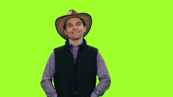 Portrait of a man in cowboy hat smiling on green background