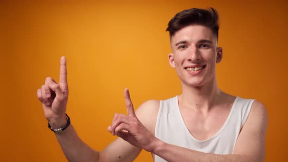 Young Man Pointing to Copy Space for Advert Yellow Background