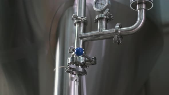 Close-up of a Male Brewer Opening a Tap for Brewing Beer From a Beer Tank To a Keg.