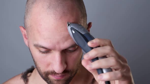 A Man Shaves His Head with a Hair Clipper