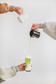 Female hands pouring matcha tea and milk into glass - PhotoDune Item for Sale