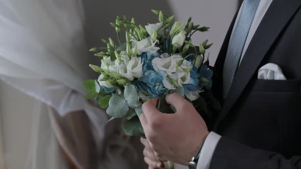Groom with Wedding Bouquet in His Hands at Home. White Shirt, Blue Tie, Jacket