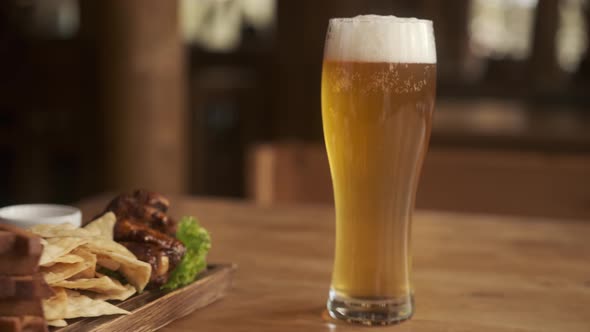 Closeup View of beer and snacks. A glass with beer and snacks on a plate on wooden table