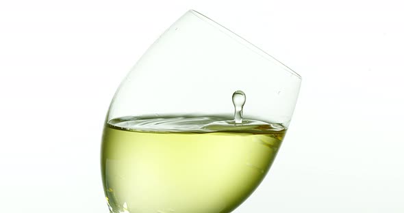 900046 Drop of White Wine falling into Glass, against White Background, Slow motion 4K