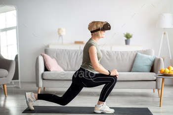 Virtual workout. Side view of senior lady in VR glasses doing lunges at home. Smart sports and / Photodune, Misc