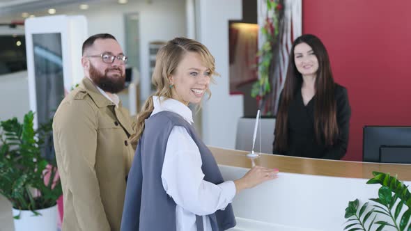 Friendly Woman Administrator Meets Buyers in the Showroom of New Cars