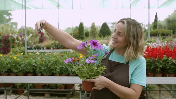 Happy Female Gardener Using Mobile Phone at Work