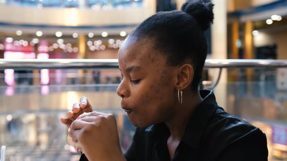 Beautiful Young Afro Woman Eating Fast Food in a Restaurant Enjoying Delicious Juicy Hamburger