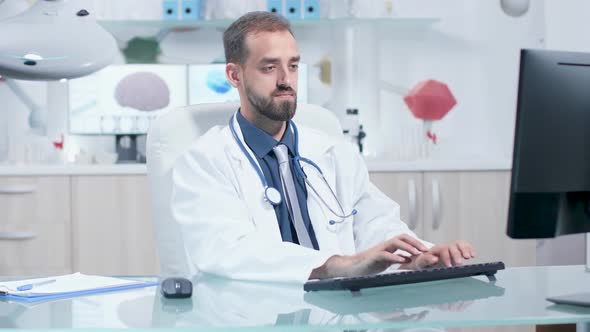 Doctor Typing on His Computer Then He Writes in Clipboard