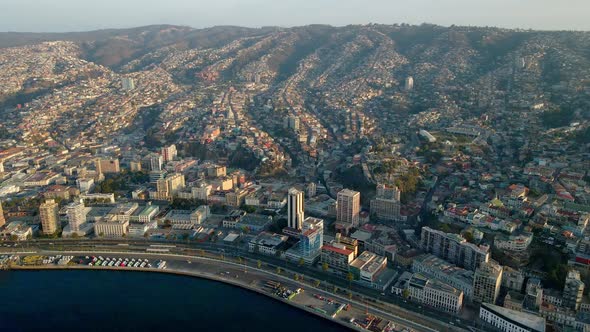 Aerial dolly in of picturesque Valparaiso hillside city buildings and sea coastline at golden hour,