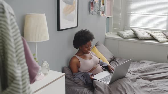 African American Woman Video Chatting on Laptop in Bed