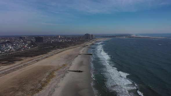 A drone view over an empty beach on a beautiful day with a few clouds. The camera dolly out over the