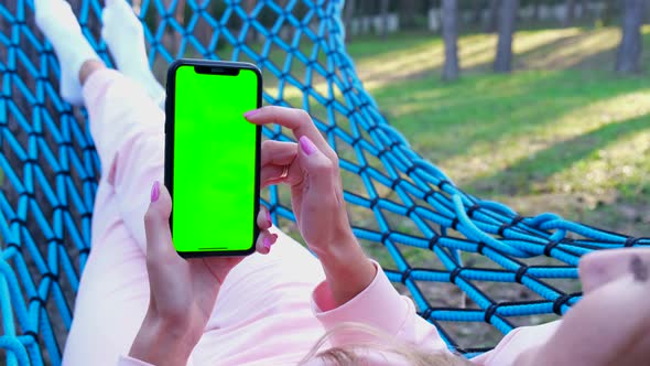 Girl Uses a Smartphone with a Chromakey Screen