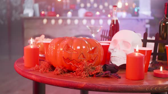 Skull and Jack-o-lantern on a Wooden Table in a Halloween Decorated Pub