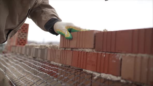 Worker builds a wall of red silicate brick. 