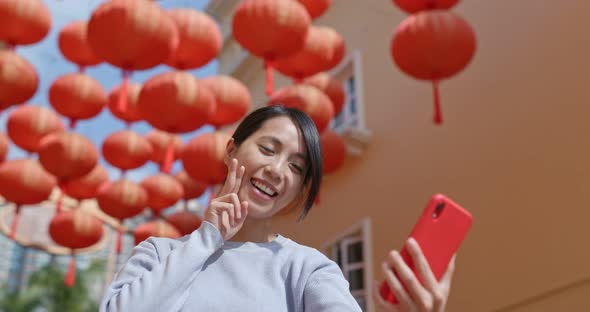 Woman take selfie on cellphone with red lantern decoration at the street