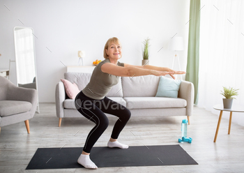Home workout concept. Beautiful mature lady in sportswear doing squats on yoga mat indoors, free / Photodune, Misc