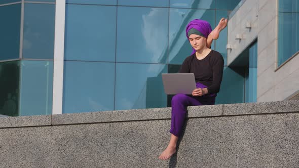 Muslim Islamic Indian Woman in Hijab Girl Yogi Female Gymnast Sitting in City with Laptop Working