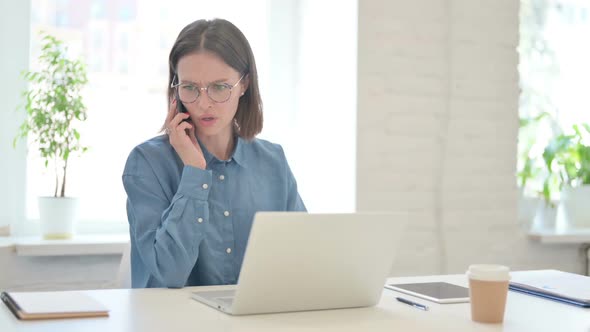 Angry Young Woman Working on Laptop and Talking on Phone