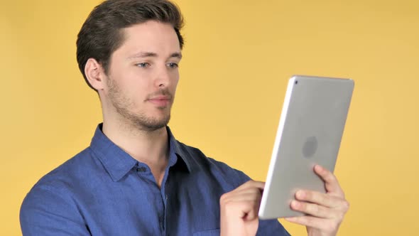 Casual Young Man Using Tablet on Yellow Background