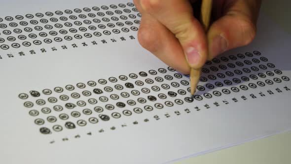 Male student hand testing doing examination test with anger. Standardized test form and answers bubb