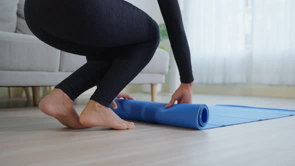 Close up short of young sportswoman hand roll out exercise mat at home.