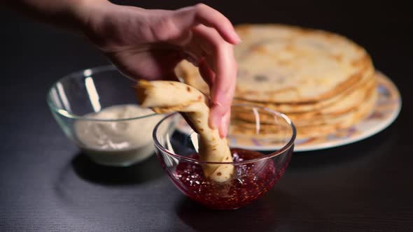 girl's hand dunks pancake in jam