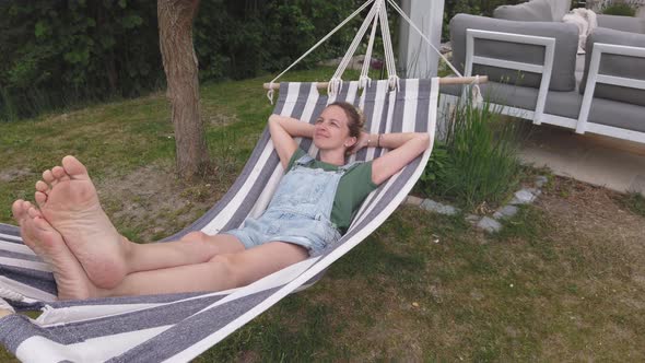 Slow motion shot of smiling woman relaxing in hammock