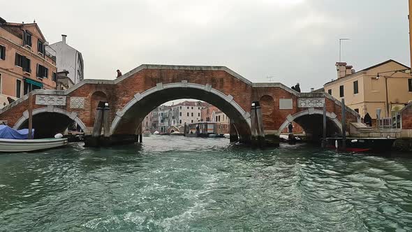 Ponte dei Tre Archi bridge in Cannaregio seen from sailing boat on canal, Venice in Italy. Slow moti