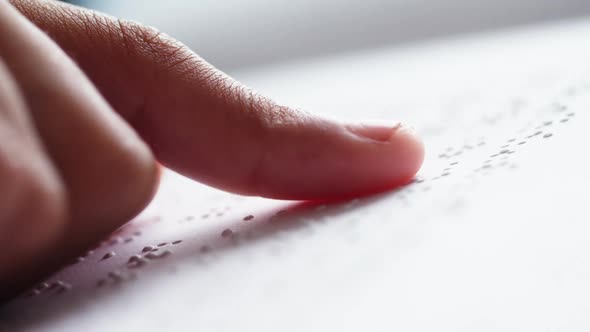 Schoolkid reading a braille book in classroom at school