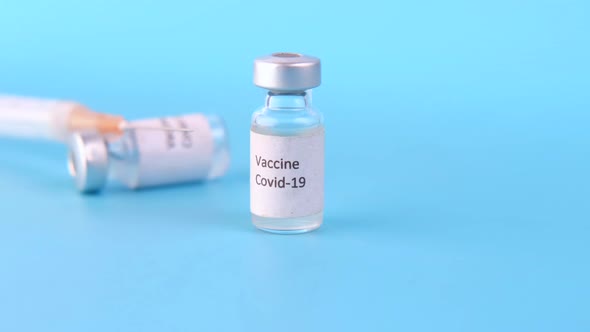 Close Up of Coronavirus Vaccine and Syringe on Blue Background
