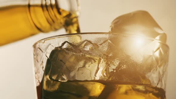 Pouring Scotch Whisky in Glass with Ice Cubes in Slow Motion alt