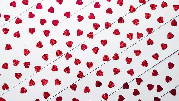 Vlentine's Day Composition. Heart Shaped Sequins Placed on White Wooden Table