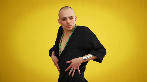 Portrait of Young Male Queer in Black Elegant Dress and Necklace Posing at Yellow Background