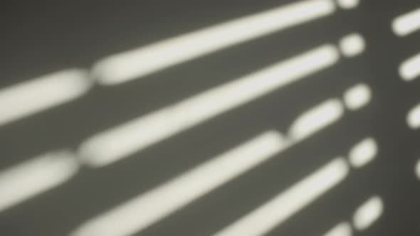 Shadows on the wall of an electric window shutter being opened in room