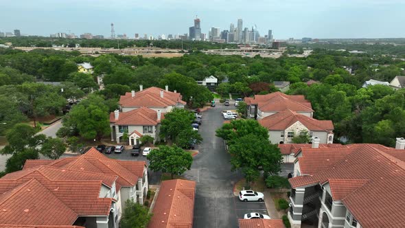 Large private gated homes and apartment community in USA. Urban city skyline in distance. Aerial pul