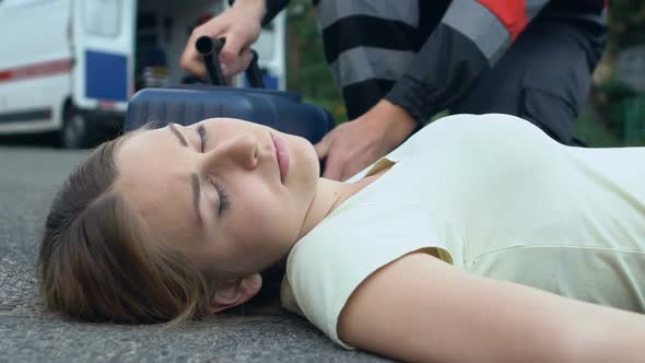 Unconscious Woman Lying on Asphalt, Paramedic Rendering First Medical Assistance