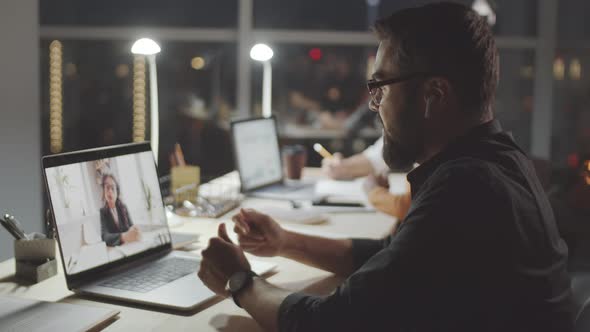 Man Video Calling on Laptop in Dark Office in Evening