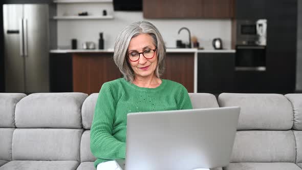 Mature Senior Woman Is Using a Laptop at Home